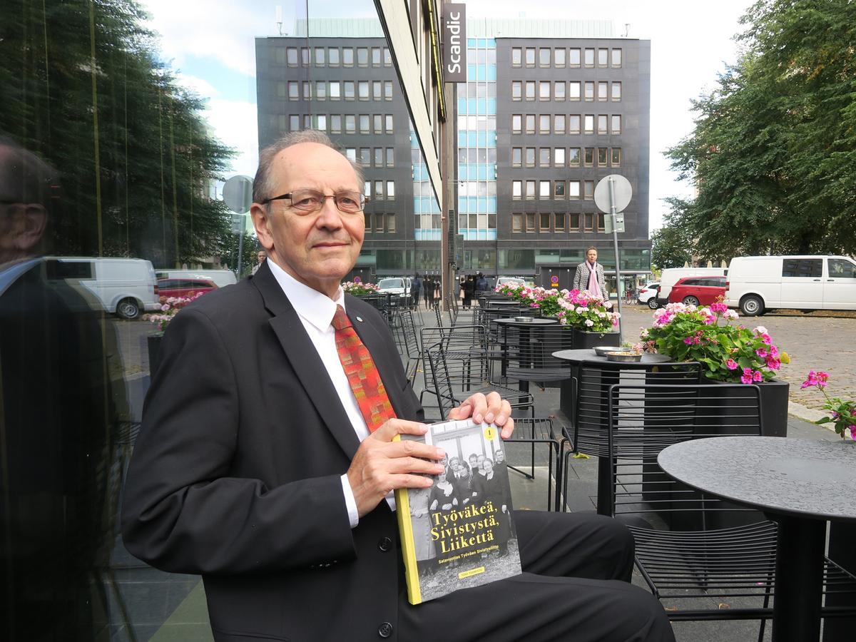 Tero Tuomisto istuu kahvilan terassilla kirja sylissään.