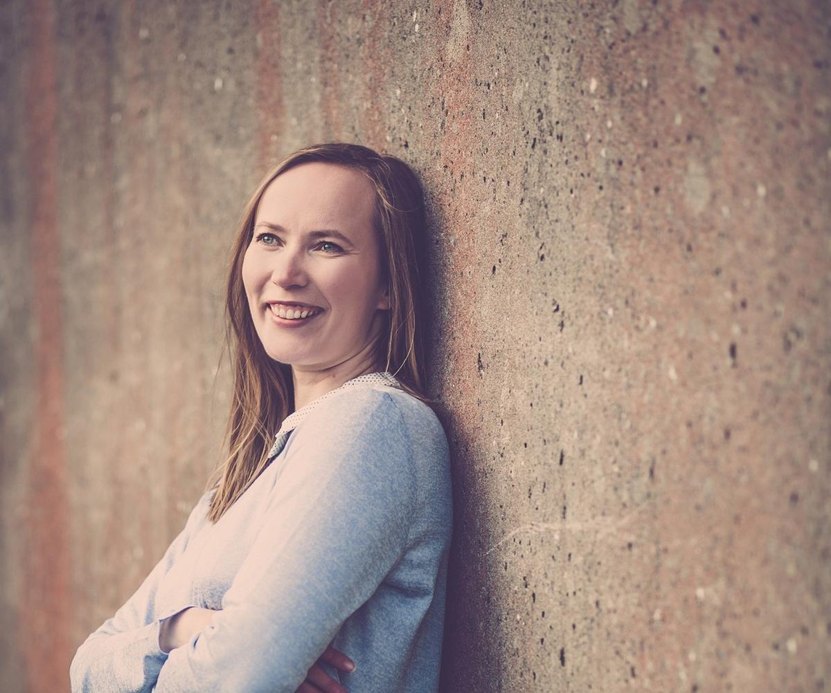 Noora Vallinkoski nojaa kädet ristissä seinään.