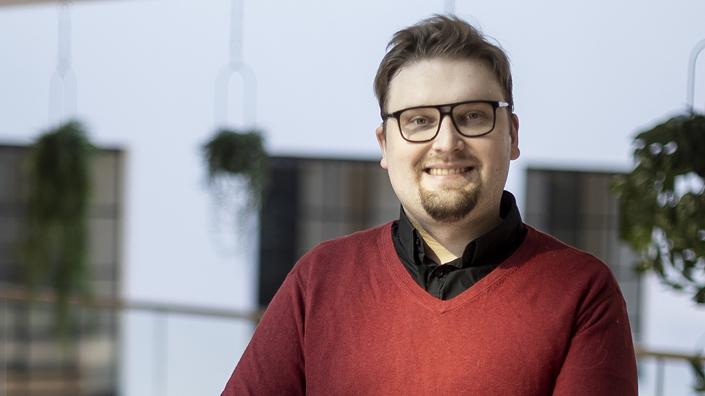 Niku Hinkka hymyilee, taustalla näkyy ikkunoita ja kasveja.