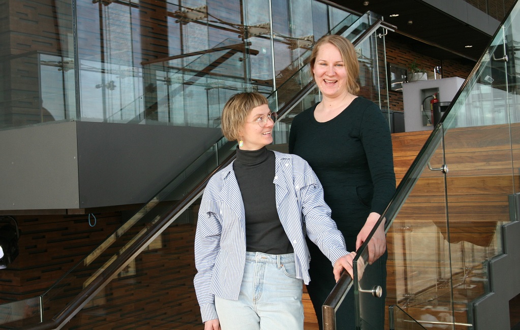 Laura Lehtinen ja Elsa Heikkilä seisovat rappusilla. Laura on kääntynyt katsomaan ylemmällä rapulla olevaa Elsaa.