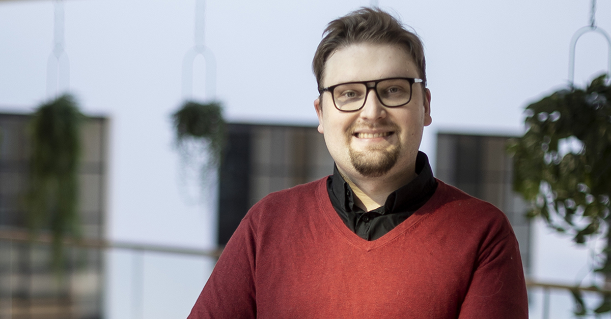 Niku Hinkka hymyilee, taustalla näkyy ikkunoita ja kasveja.