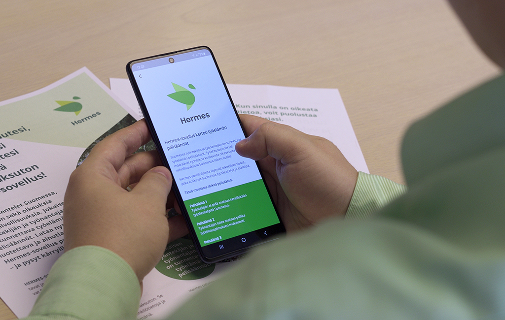 Työntekijällä on kädessä puhelin, jossa on auki Hermes-sovellus.