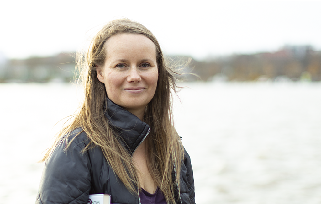 Hymyilevä Inari Juntumaa, taustalla vettä ja vastarantaa.