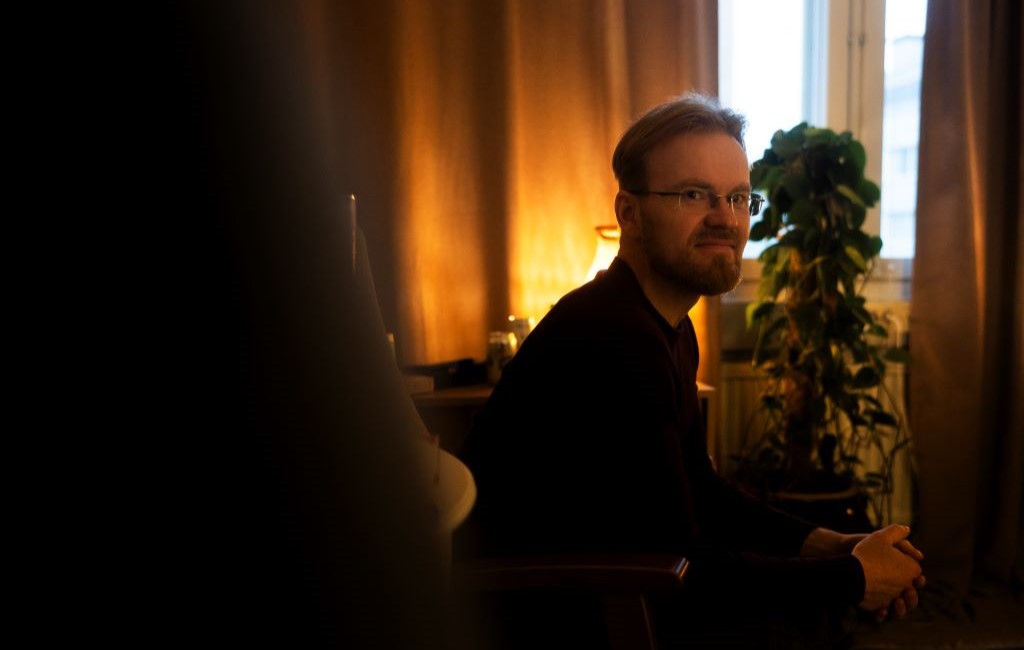 Mies istuu hämärässä valaistuksessa.