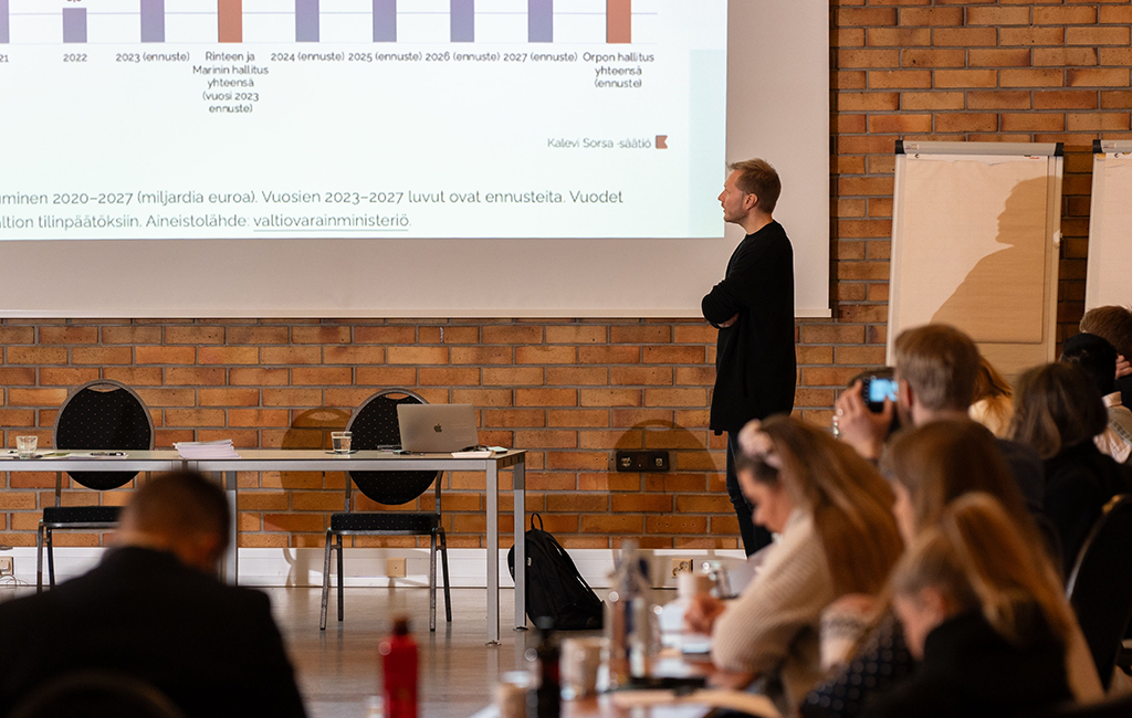 Lauri Finer kertoo yleisölle valtion velasta ja sen ennusteesta.